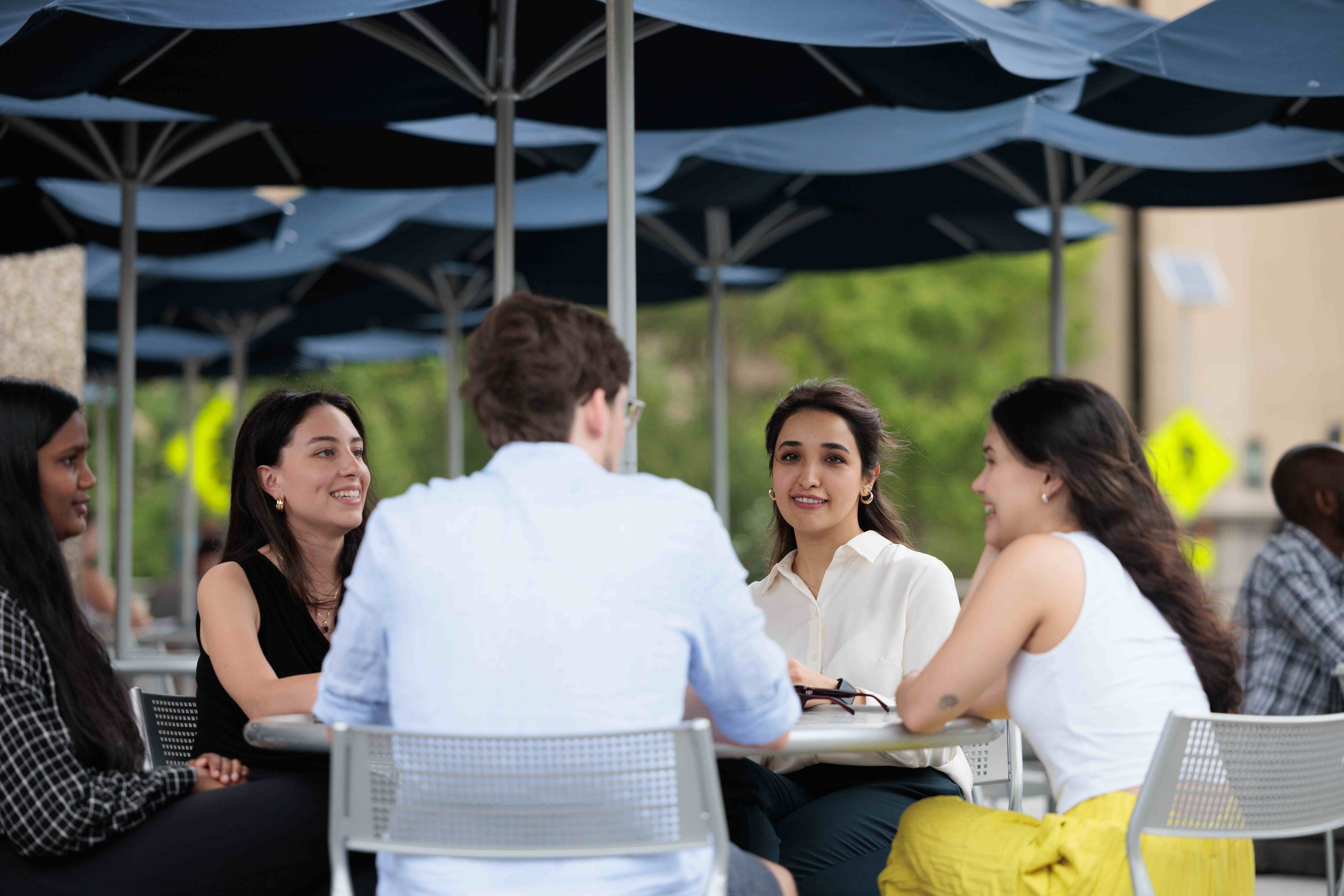 A group of students seated outside at a table on GW campus