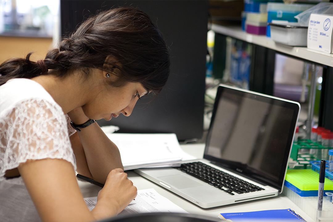 A GW student writing on a piece of paper